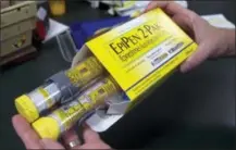  ?? THE ASSOCIATED PRESS ?? A pharmacist holds a package of EpiPens epinephrin­e auto-injector, a Mylan product, in Sacramento, Calif.