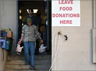  ?? (Arkansas Democrat-Gazette/Stephen Swofford) ?? Charles Fletcher and Ty Golleher carry turkeys to the back of the Little Rock Compassion Center where they will be cooked on Tuesday.