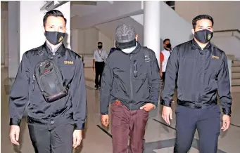  ??  ?? Ahmad Hasrul (centre) being escorted by the MACC personnel at the Session Court lobby yesterday. – Bernama photo