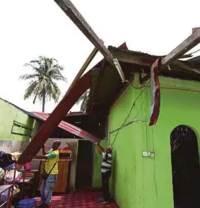  ?? (Foto Sharul Hafiz ZAM/BH) ?? Zaini (kiri) bersama jiran memeriksa rumahnya di Kampung Pida 3, Jitra yang musnah dipukul ribut.