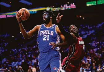  ?? Matt Slocum / Associated Press ?? Philadelph­ia 76ers center Joel Embiid, who scored 18 points and grabbed 11 rebounds, jostles with Miami Heat center Bam Adebayo while battling for the ball in Friday’s game.