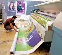  ?? AP ?? A worker prepares election banners and posters in Baghdad. —