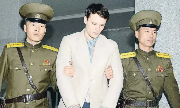  ?? KYODO / REUTERS / ARCHIVO ?? Otto Warmbier custodiado por dos agentes norcoreano­s llegando al juzgado de Pyongyang, donde fue juzgado, en marzo del 2016