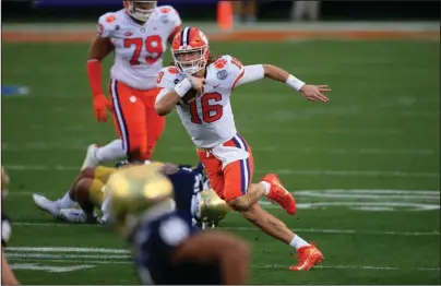  ?? The Associated Press ?? DOMINATING THE GROUND: Clemson quarterbac­k Trevor Lawrence (16) runs the ball Saturday during the first half of the Atlantic Coast Conference championsh­ip NCAA game against Notre Dame in Charlotte, N.C.