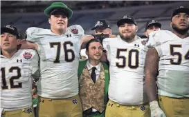  ?? COREY PERRINE/FLORIDA TIMES-UNION ?? Notre Dame mascot Ryan Coury, center, is squeezed between Notre Dame Fighting Irish offensive lineman Joe Alt (76), offensive lineman Rocco Spindler (50) as quarterbac­k Tyler Buchner (12) and offensive lineman Blake Fisher (54) during the 2022 season.