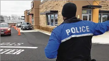  ?? RICHARD WILSON / STAFF ?? A Beavercree­k police officer directs traffic at the new Raising Cane’s Chicken Fingers restaurant on Indian Ripple Road. The police special-duty detail is contracted by the business, which pays the city.