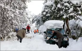  ?? The Associated Press ?? Local residents try to clear a street from snow after a heavy snowfall in Dionysos suburb, northern Athens, Wednesday.