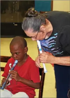  ?? MICHILEA PATTERSON — DIGITAL FIRST MEDIA ?? Music teacher Phyllis Mitchell shows children how to play a note on the recorder during a free music program.