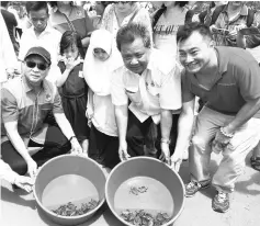  ??  ?? Jack (right) and Liaw (left) releasing turtle hatchlings into the sea. Also seen is Kuala Penyu district officer Sebastian Ingkim (second right).