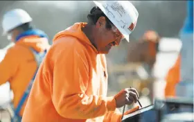  ?? David Zalubowski / Associated Press ?? Foreman Rodney Strouse programs a tablet to control Sam, a semi-automated mason, as it works on the facade of a school in Englewood, Colo.