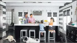  ??  ?? Associated Press Interior designer Vern Yip is shown in his Atlanta home with his family and dogs. Families with pets have several options for durable, attractive flooring that will stand up to even the most rambunctio­us pets.