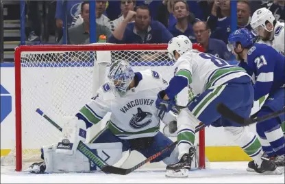  ?? The Associated Press ?? Vancouver Canucks goaltender Anders Nilsson makes a save against Tampa Bay Lightning forward Brayden Point as Jay Beagle (83) and Erik Gudbranson, right, defend during first-period NHL action on Thursday in Tampa, Fla. The Canucks won 4-1.