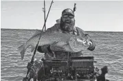  ?? DAVID EURELL ?? Scott Thomas of Grumpy’s Tackle in Seaside Park holds a striped bass he landed from a kayak during the 2023 spring bass run.