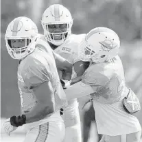  ?? TAIMY ALVAREZ/SOUTH FLORIDA SUN SENTINEL ?? Dolphins defensive end Nate Orchard (left) and safety Minkah Fitzpatric­k hold back teammate tight end Dwayne Allen after a heated exchange between Allen and defensive tackle Charles Harris during training camp.