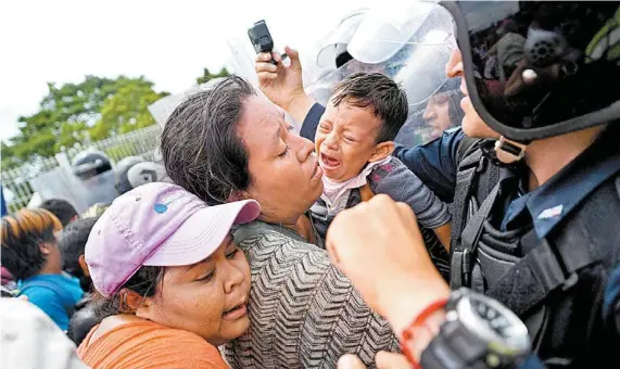  ??  ?? Luego de que lograron cruzar el primer retén, los migrantes ya eran esperados por policías con uniformes antimotine­s. PEDRO PARDO/AFP