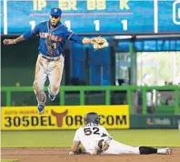  ?? PATRICK FARRELL/MIAMI HERALD ?? Miami Marlins base runner Rafael Ortega slides safely into second base during the first inning as New York Mets shortstop Amed Rosario bobbles the ball.