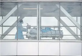  ?? GRAHAM HUGHES THE CANADIAN PRESS FILE PHOTO ?? A health-care worker pushes a patient across a connecting bridge at a hospital in Montreal. A new report says misinforma­tion about COVID contribute­d to more than 2,800 Canadian deaths.