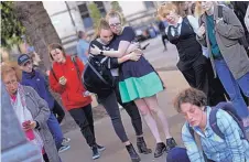  ?? EMILIO MORENATTI/ASSOCIATED PRESS ?? People stand next to flowers after a vigil at Albert Square in Manchester, England, on Tuesday, the day after the suicide attack at an Ariana Grande concert that left at least 22 people dead.