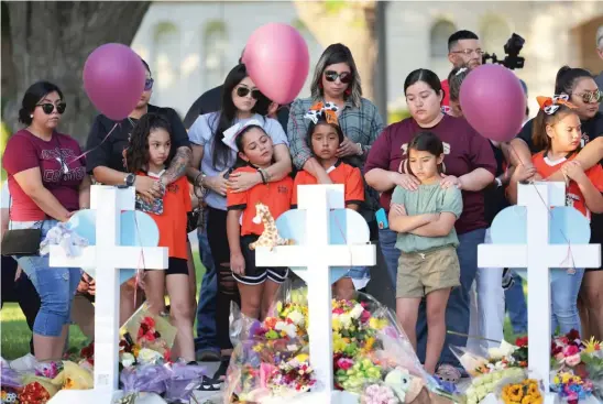  ?? MICHAEL M. SANTIAGO/GETTY IMAGES ?? People visit memorials on Thursday for the victims of Tuesday’s mass shooting at Robb Elementary School in Uvalde, Texas. Nineteen children and two adults were killed at the school when an 18-year-old gunman entered an unlocked door and barricaded himself in a classroom with the victims.