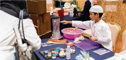  ??  ?? A student from Idrissi Internatio­nal School showing a visitor how to recycle paper to make parchment to write calligraph­y on at the Golden Age Invention Exhibition 2018.