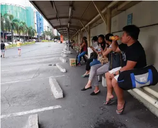  ?? ROBERT OSWALD P. ALFILER / PNA ?? STRANDED. Several passengers are waiting for public transport at a UV express terminal on Tuesday (March 17, 2020) in Cubao, Quezon City.