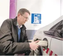  ?? GAVIN YOUNG ?? Eric MacNaughto­n, Calgary’s transporta­tion co-ordinator for climate programs, demonstrat­es one of the City Hall parkade electric vehicle charging stations.