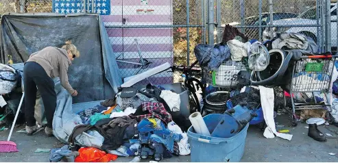  ?? GREGORY BULL / THE ASSOCIATED PRESS ?? A woman who was camping in downtown San Diego sorts through her belongings on a sidewalk that was being sprayed with a bleach solution to fight a deadly hepatitis A outbreak.