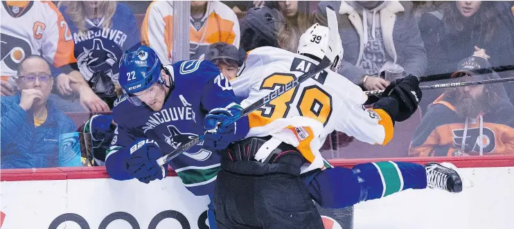  ?? — THE CANADIAN PRESS ?? Vancouver Canucks left wing Daniel Sedin is checked by Philadelph­ia Flyers defenceman Mark Alt during the second period Thursday at Rogers Arena.