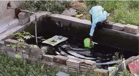  ?? — AP. ?? Tapping any source: A man fetching water from a concrete tank in an upcoming residentia­l neighbourh­ood due to the water shortage in Bangalore.