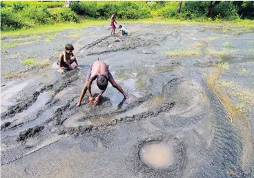  ?? SAURABH DAS / THE ASSOCIATED PRESS ?? Children play on farmland destroyed by asbestos sediments in Roro, India, in 2014. More than 50 countries have banned all forms of asbestos, but the industry has found new markets in developing countries, particular­ly in Asia.