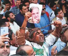  ?? AP ?? A PML-N supporter holds a picture of Shahbaz Sharif during a rally outside the court in Lahore yesterday. The court ordered Sharif remanded in custody for 10 days.