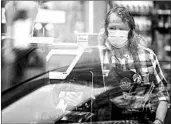  ?? TING SHEN/THE NEW YORK TIMES ?? A cashier wears a face mask amid the pandemic April 14 in Washington. Some chains are now ending “hero” raises.