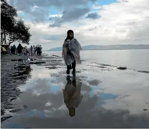  ?? AP ?? Refugees wander the foreshore after their arrival at Skala Sikamias, Lesbos island, Greece.
