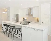  ??  ?? The bright, white kitchen in the Stirling show home by Cedarglen Homes has a long quartz-topped island with seating for four.