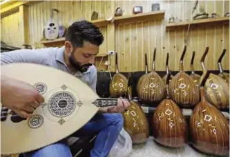  ??  ?? Ali Khalifeh, a lute-maker, tries a oud at a shop.