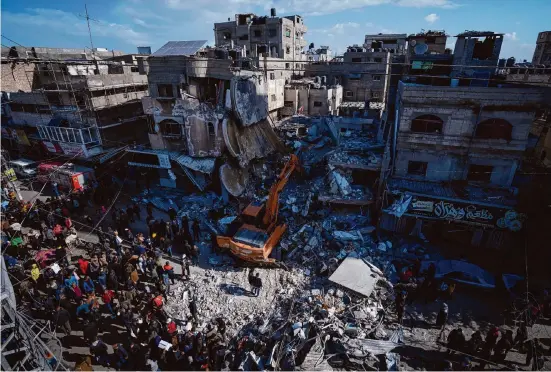  ?? Fatima Shbair/Associated Press ?? Palestinia­ns search for bodies and survivors last week in the rubble of a residentia­l building destroyed in an Israeli airstrike in Rafah, Gaza Strip.
