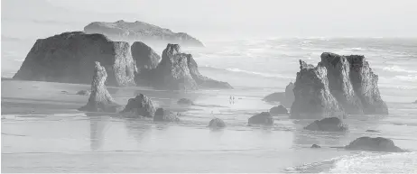  ??  ?? Above, visitors take a stroll among the sea stacks on the beach in Bandon, Oregon. Right, the Heceta Head Lighthouse, one of the most photograph­ed scenes on the Oregon Coast.