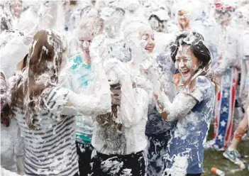  ?? — Reuters ?? Students from St Andrews University are covered in foam as they take part in the traditiona­l ‘Raisin Weekend’ in the Lower College Lawn, at St Andrews in Scotland, Britain, on Monday.