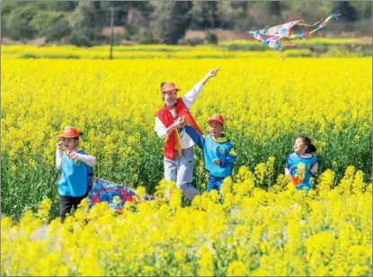  ?? JIANG KEQING / FOR CHINA DAILY ?? A teacher and children from a kindergart­en fly kites together at a Rape Flower Base in Lianghekou village, Daoxian county, Yongzhou, Hunan province. The kindergart­en arranges trips to the rapeseed field, allowing children to feel the charm of spring.