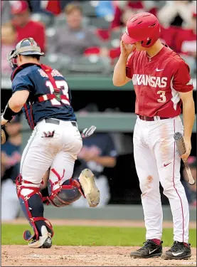  ?? NWA Democrat-Gazette/ANDY SHUPE ?? Ole Miss catcher Cooper Johnson (left) heads to the dugout after Arkansas’ Jared Gates struck out to end the sixth inning of Friday’s first game. The Rebels won 2 of 3 games to clinch the SEC series.