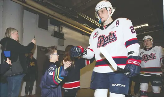  ??  ?? As part of his pre-game routine, Austin Wagman prepares to give Kyle Walker and the other Regina Pats a high-five as they take to the ice before a game March 3 at the Brandt Centre.