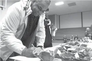  ?? Staff photo by Jerry Habraken ?? Robert High places a bid on one of the handmade ceramic bowls made by the Texas High School ceramics students Thursday afternoon at the 17th annual Bramlett Beans and Cornbread community fundraiser.