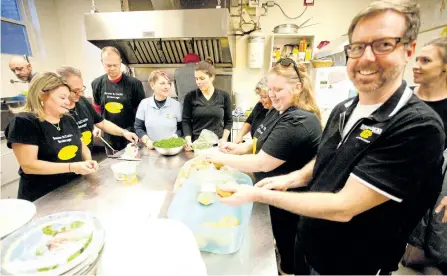  ?? JASON BAIN/EXAMINER ?? Bowes & Cocks realtors, including Paul Mason slicing buns at right, help prepare a roast beef dinner for about 160 people at One Roof Community Diner on Brock Street on Thursday. The brokerage supported the effort as part of its #galleryofg­iving...