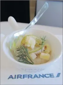  ??  ?? An amuse-bouche of scallops with green apple, lime zest and Comté cheese in business class on Air France.
