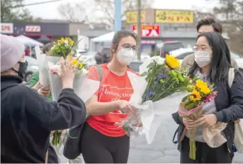  ??  ?? Mourners prepare to lay flowers Wednesday at a makeshift memorial outside of the Gold Spa in Atlanta.