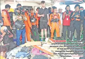  ?? GambarAFP ?? PENGAMAL media merakam serpihan barangan dan bangkai pesawat Lion Air yang terhempas di laut pada Isnin. Operasi mengesan bangkai pesawat dan mayat penumpang masih diteruskan.