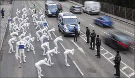  ?? SEBASTIAN GOLLNOW / DPA VIA AP ?? Greenpeace demonstrat­ors in bodysuits protest pollution caused by vehicle emissions while police guard the road in Stuttgart, Germany, earlier this week. A poster (front, left) reads: Clean air is our right.