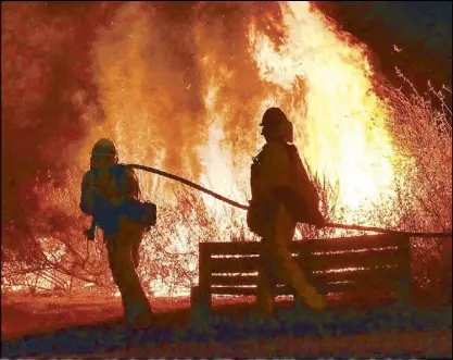  ?? AP ?? Firefighte­rs battle to contain a brush fire in the foothills outside Calabasas in Los Angeles Saturday.