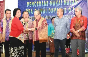  ??  ?? Uggah (third right) presents a certificat­e to a participan­t who had completed the traditiona­l Iban sarong-making course, witnessed by Robert (left), Gerald (second right), Betong Resident Friday Belik (right) and others.