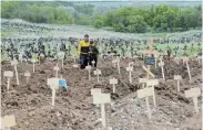  ?? Picture: ALEXANDER ERMOCHENKO/REUTERS ?? SURROUNDED BY DEATH: People stand among new graves at a cemetery in Staryi Krym outside Mariupol, Ukraine, on Sunday